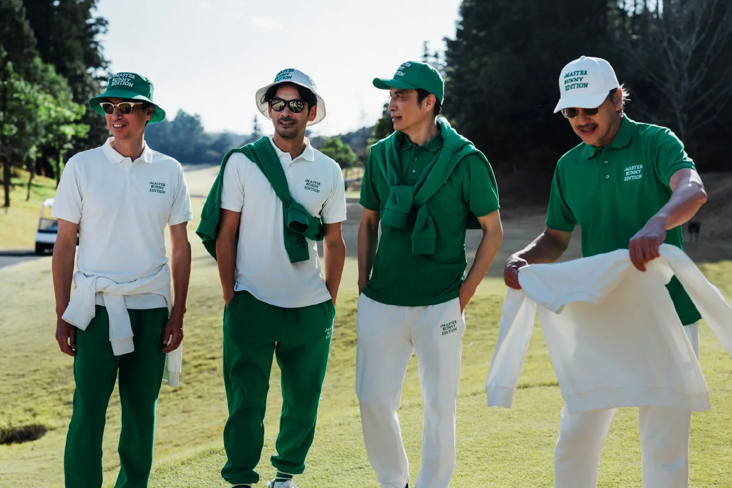 ゴルフウェアを着た4人の男性が、ゴルフ場と思われる場所に立っている様子。