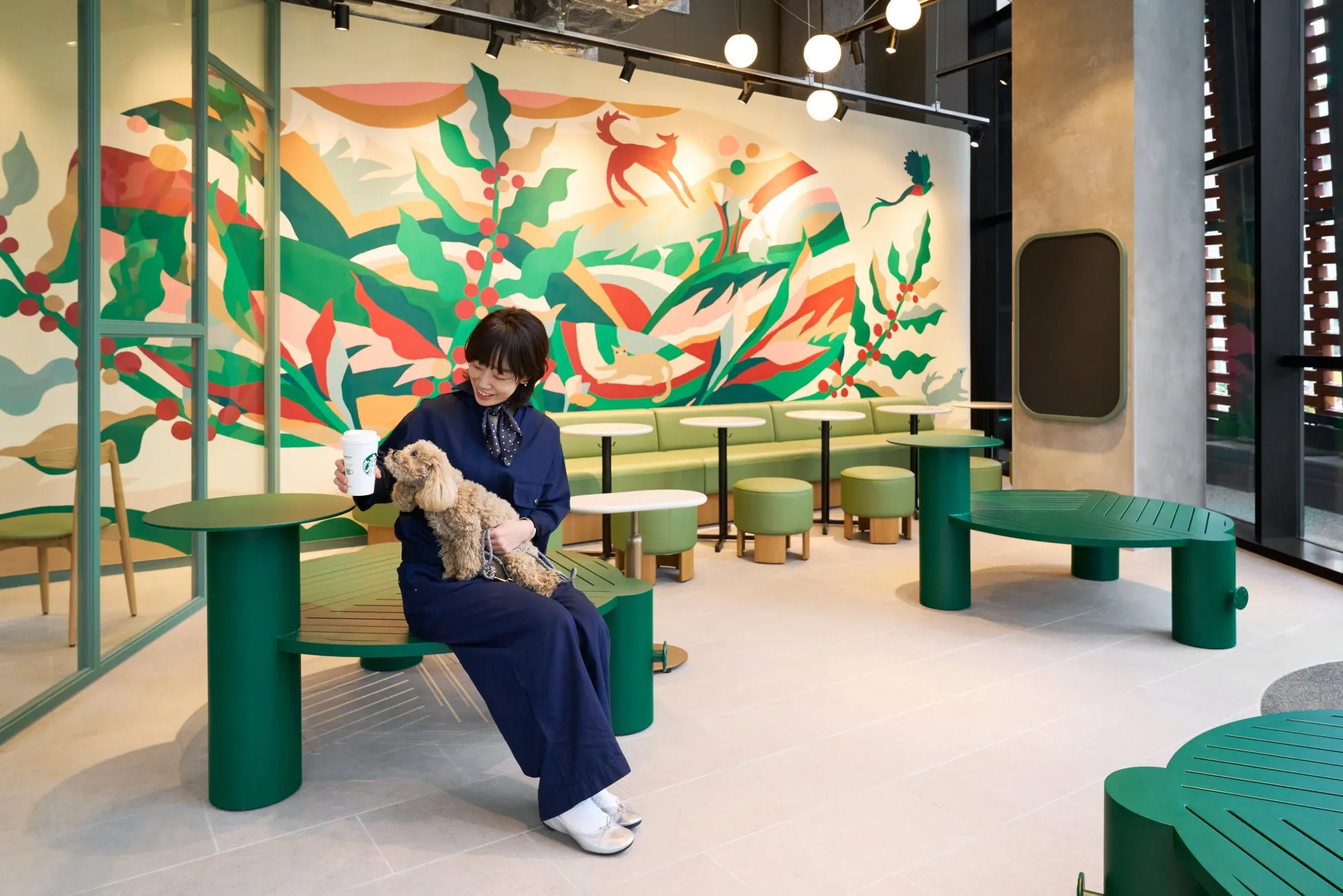 スターバックスの店内で、女性が犬を抱きかかえながらコーヒーカップを持っている様子