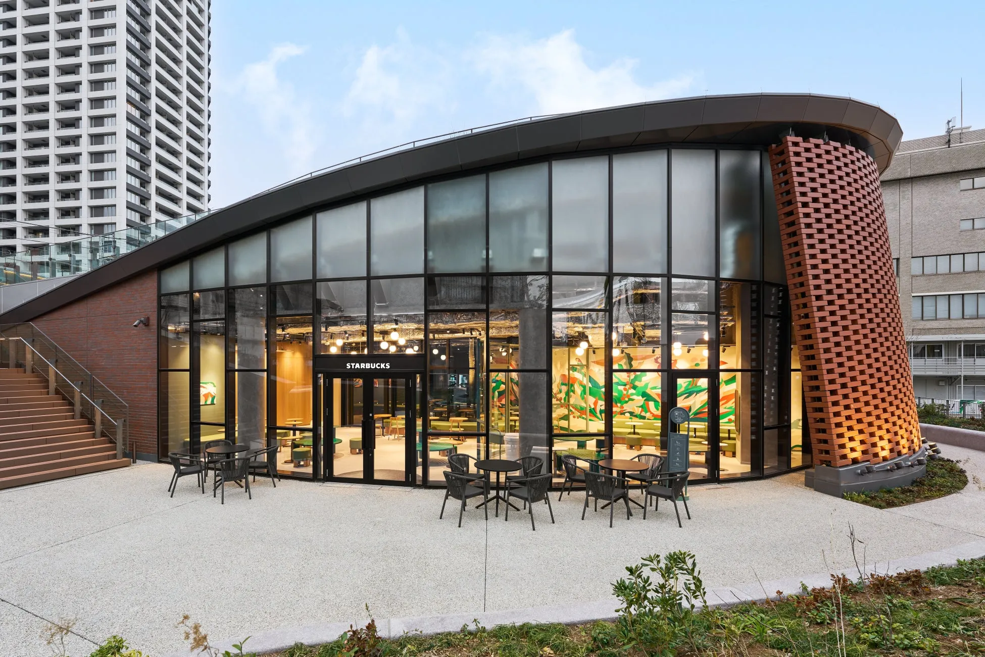 スターバックスの店舗の外観。大きなガラス窓とレンガ造りの壁、テラス席