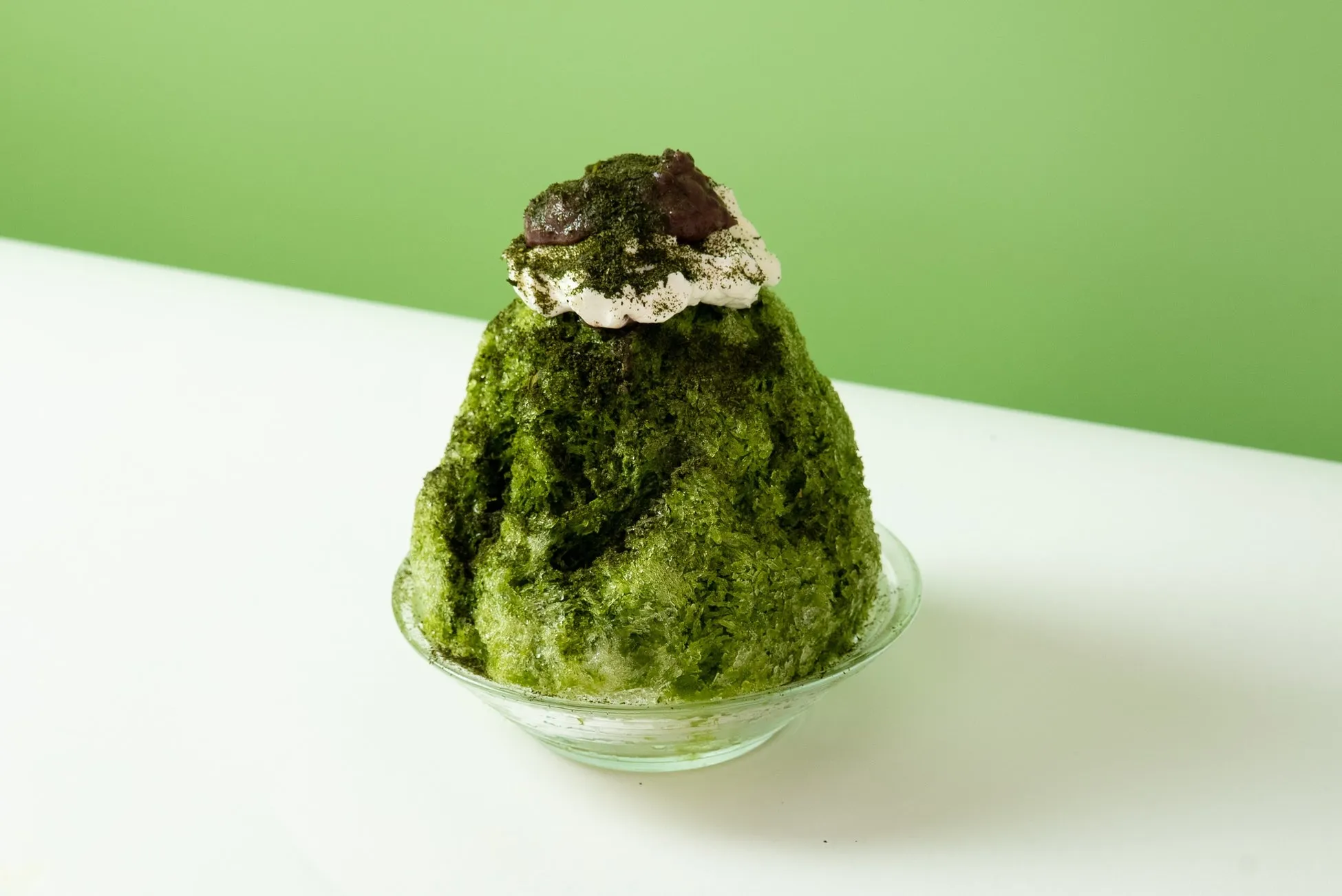 抹茶のかき氷の写真。抹茶のかき氷の上に、ホイップクリームと小豆がトッピングされている。