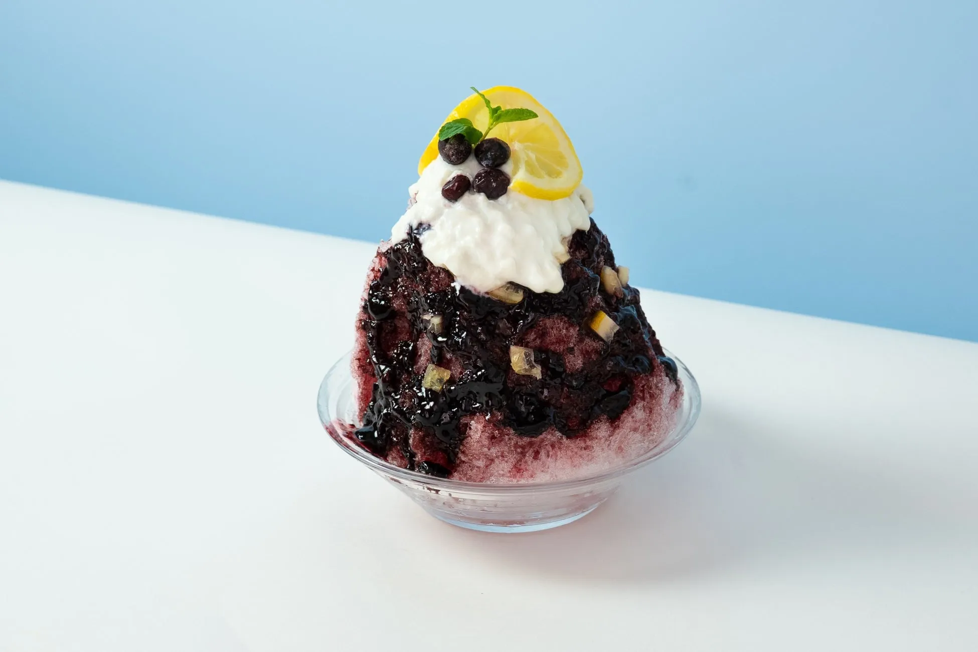 ブルーベリーのかき氷。白いクリーム、レモン、ミント、ブルーベリーがトッピングされている。