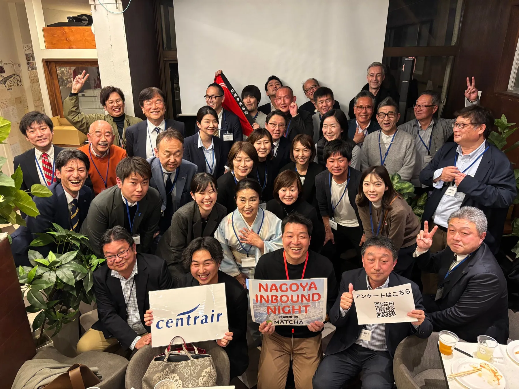 グループ写真。多くの人が集まっており、笑顔で写っている。centrair、NAGOYA INBOUND NIGHT、アンケートに関する看板を持っている人もいる。