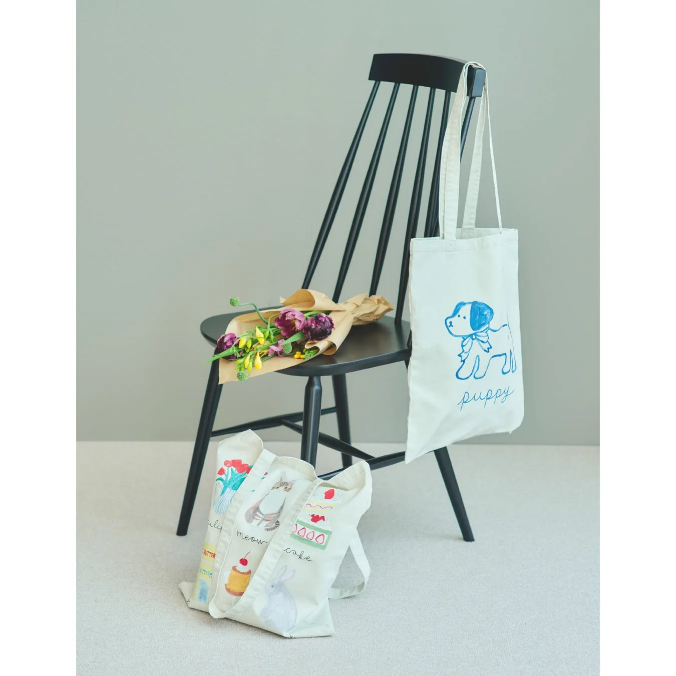 黒い椅子に花束と、犬のイラストが描かれたトートバッグ
