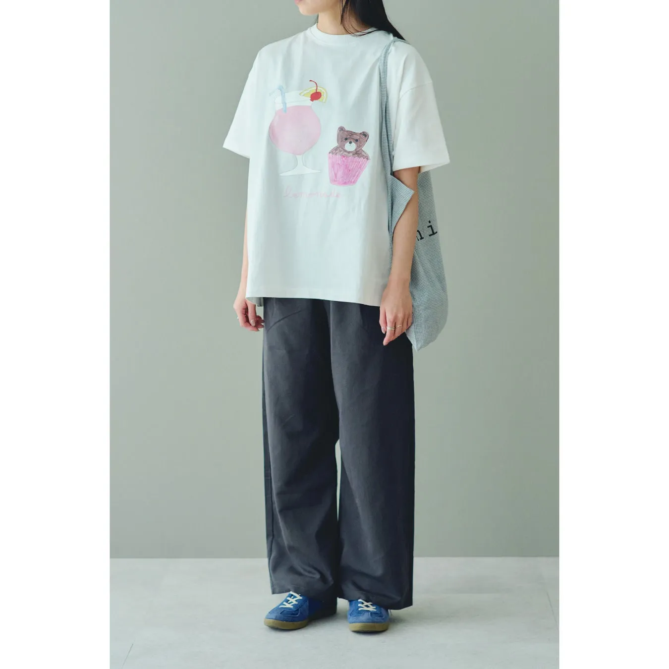 白いTシャツにイラストが描かれた女性の全身写真