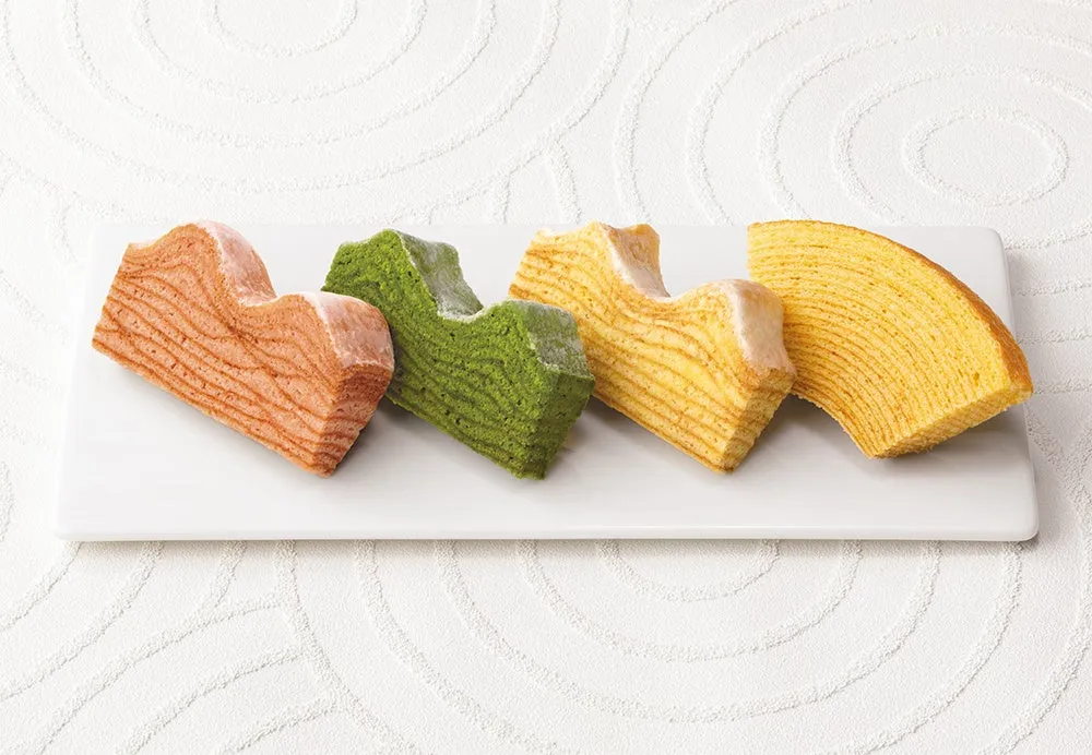 ハート型にカットされたバウムクーヘンが白いお皿に並べられた写真。オレンジ、抹茶、黄色など、様々な色合いのバウムクーヘンが並んでおり、見た目にも美しい。