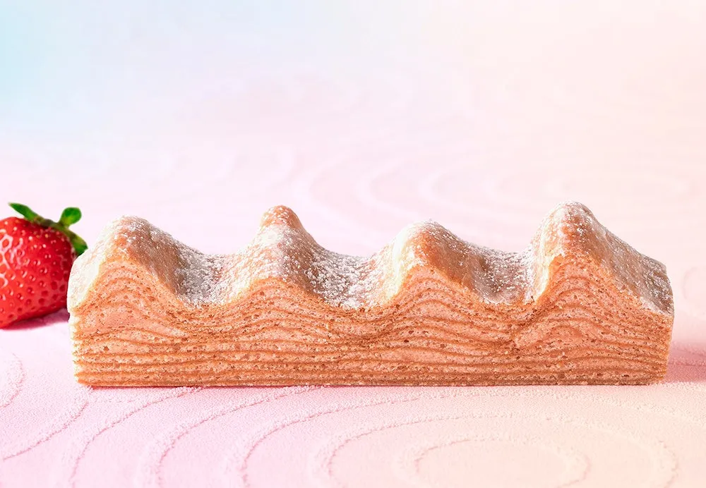 いちごのバウムクーヘンが写った写真です。ピンク色の背景に、バウムクーヘンと新鮮ないちごが配置されています。