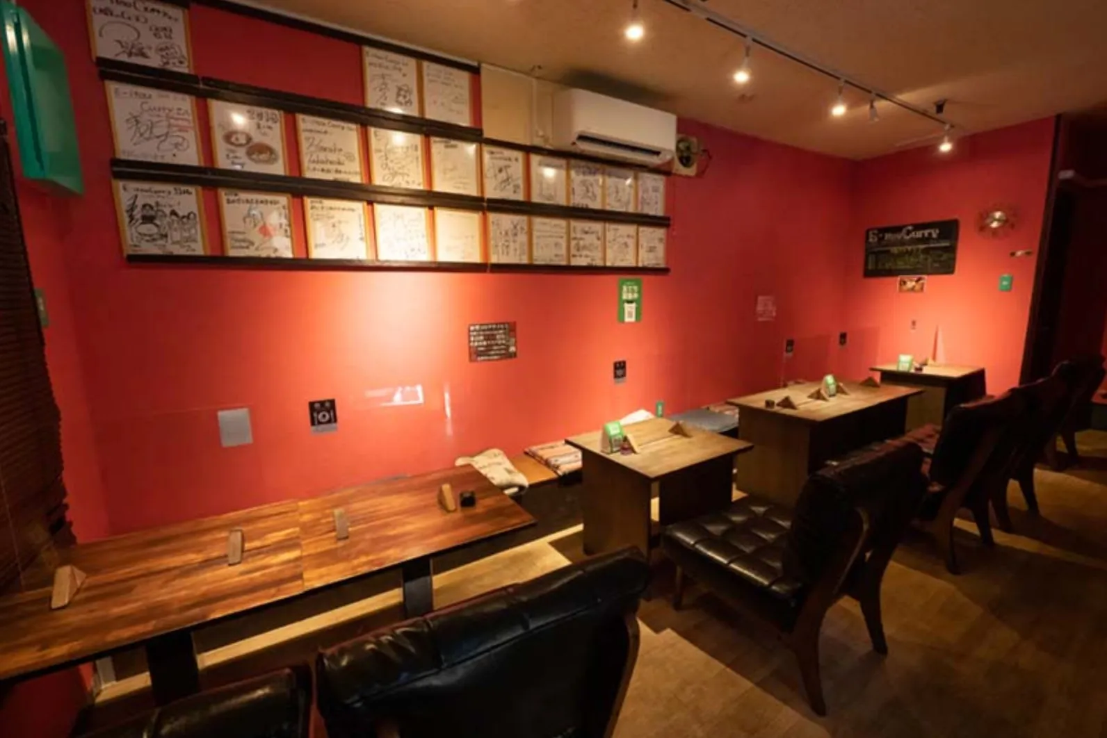店内にはテーブル席と座敷席があり、壁にはサインが飾られているカレー屋さんの内観です。