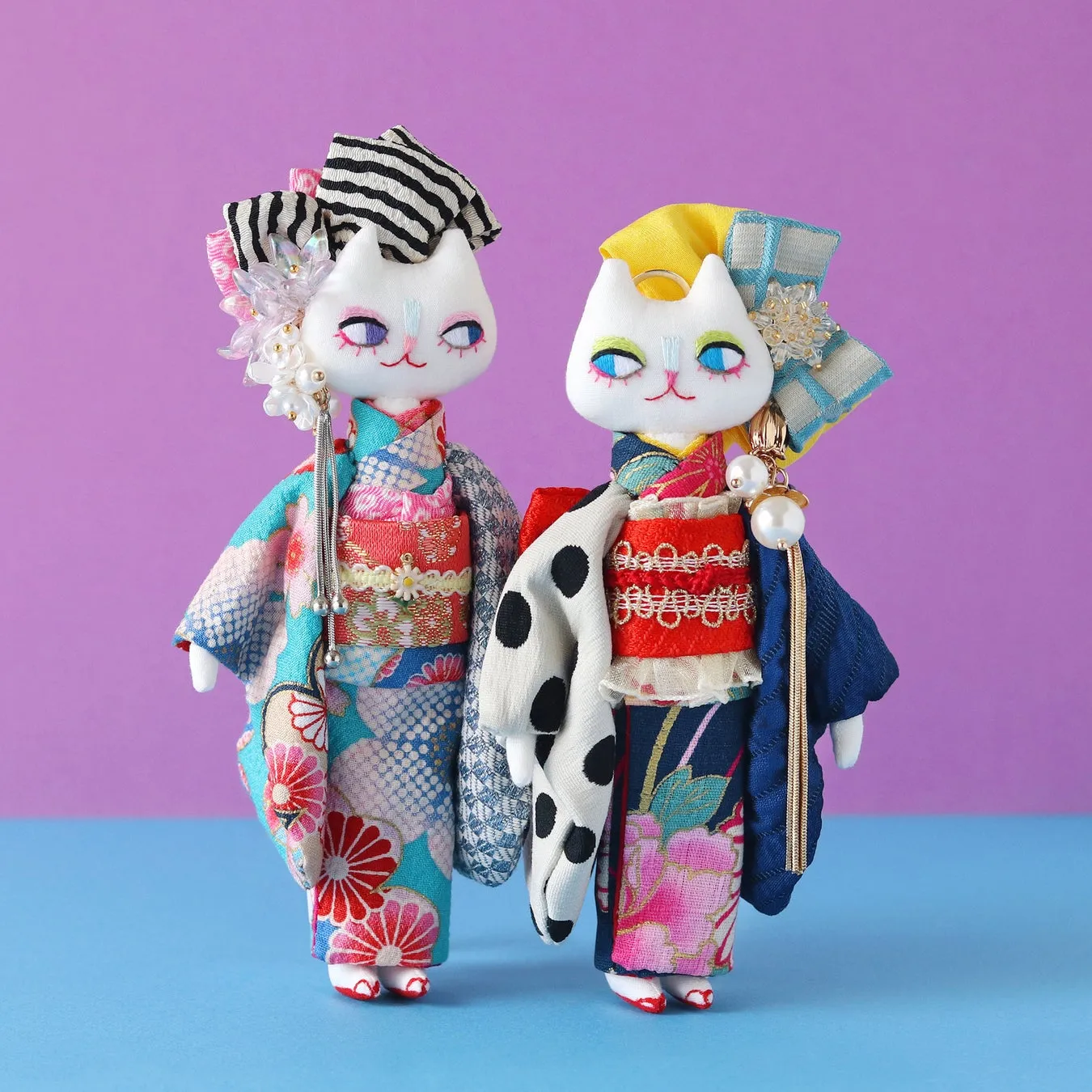 着物を着た猫のぬいぐるみ2体。背景は紫と青。