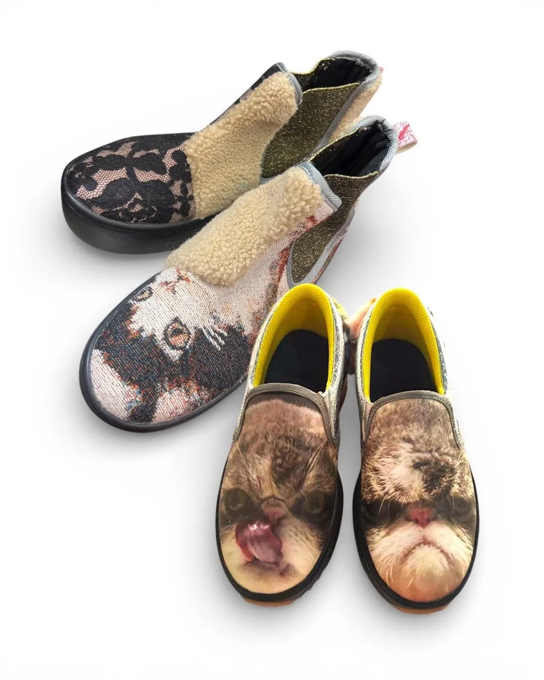 3足のユニークなデザインのスリッポンが白の背景に並んでいます。上部には、黒のレース模様と、ベージュのモコモコした素材と金色のアクセントが施されたスリッポンが見えます。中央のスリッポンは、複雑な織り模様とベージュのモコモコした素材が組み合わされています。下部の2足のスリッポンは、猫の顔がプリントされています。それぞれに黒いソールと黄色いインナーが施されています。