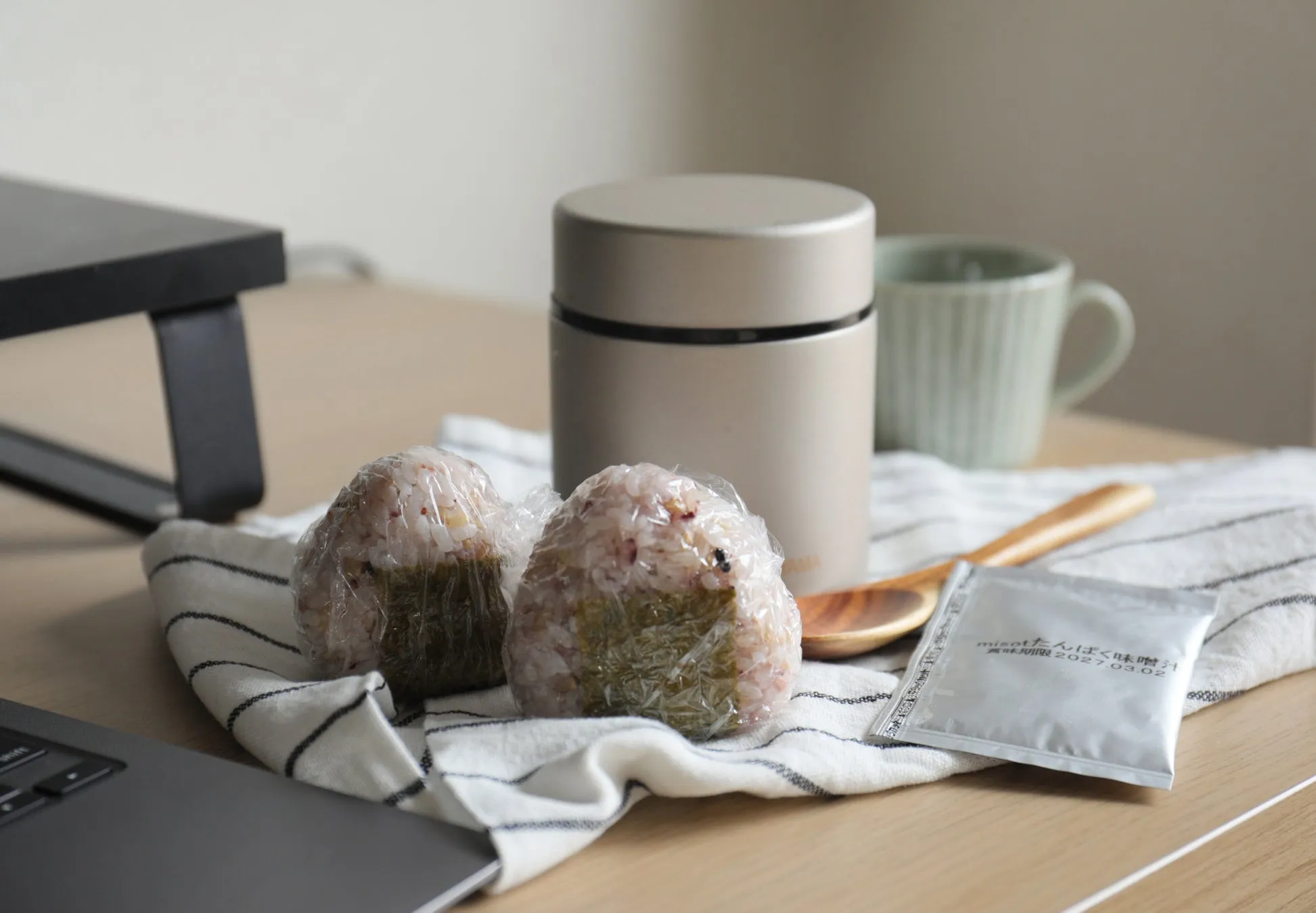 おにぎり、スープジャー、マグカップなどが写っている写真です。