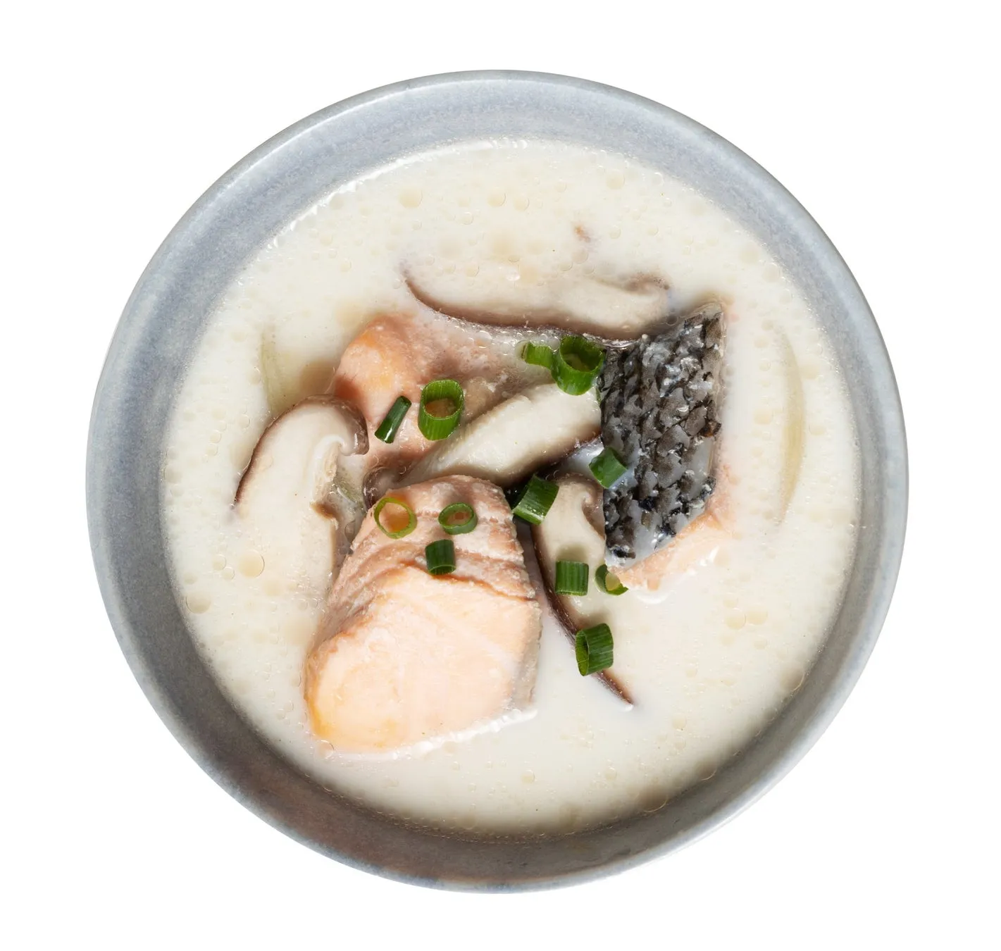 サーモンとキノコが入った白いスープが、青い縁の丼に入っている写真。