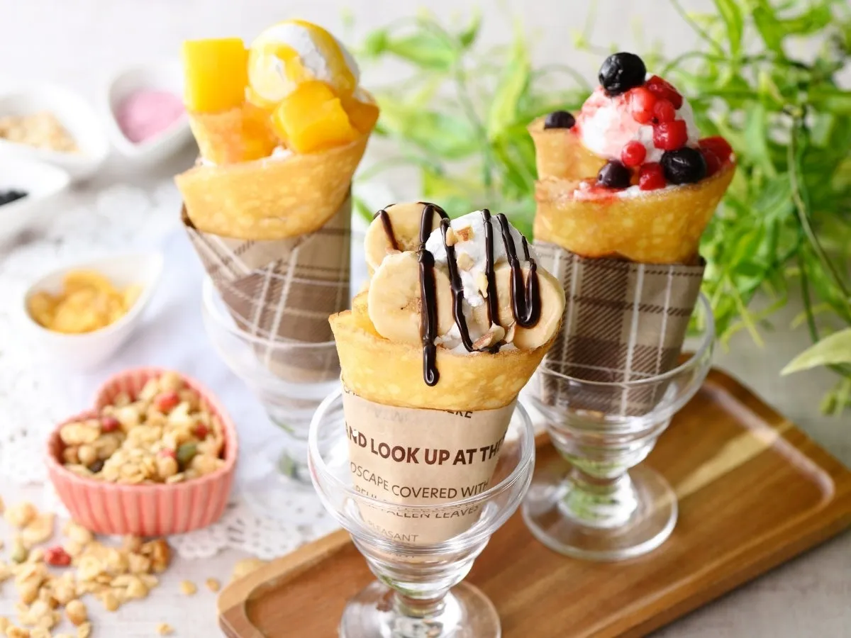 3種類のフルーツクレープがグラスに入って並んだ写真。マンゴー、バナナ、ベリーがトッピングされている。