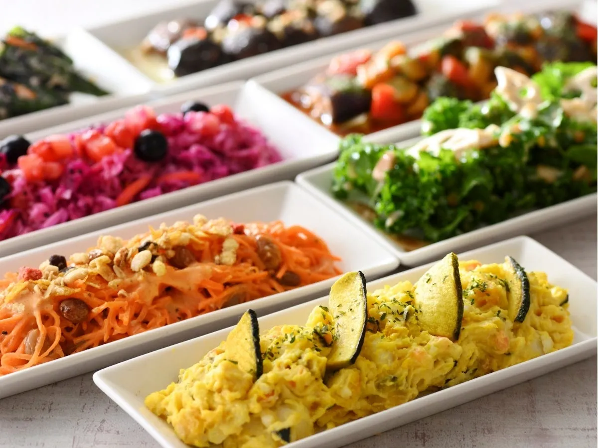 様々な惣菜が並んだ写真。彩り豊かで、野菜をふんだんに使った料理が特徴的。