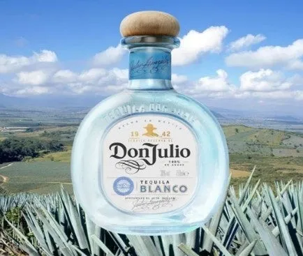 ドンフリオのテキーラブランコのボトルが、空と風景を背景に置かれています。