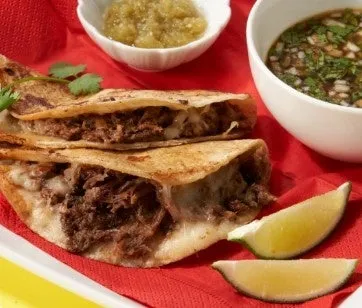 トルティーヤに包まれた牛肉料理で、ソースとライムが添えられています。