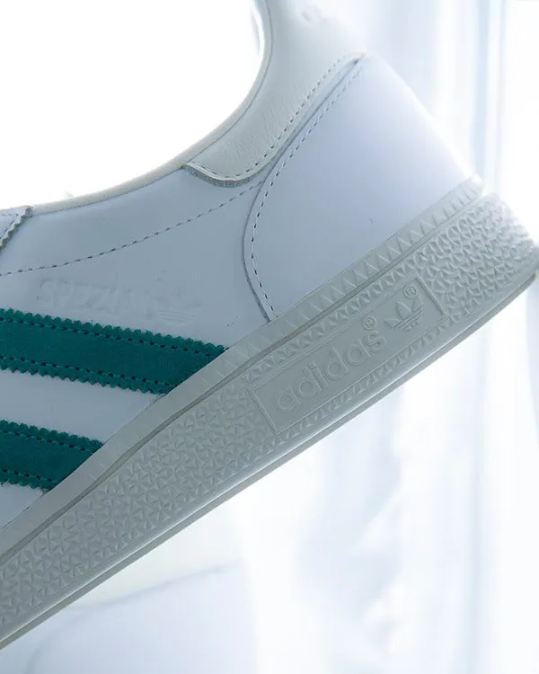 アディダスの白いスニーカーのクローズアップ写真。スニーカーの側面には、緑色の3本のストライプ、'SPEZIAL'の文字、アディダスのロゴが見える。