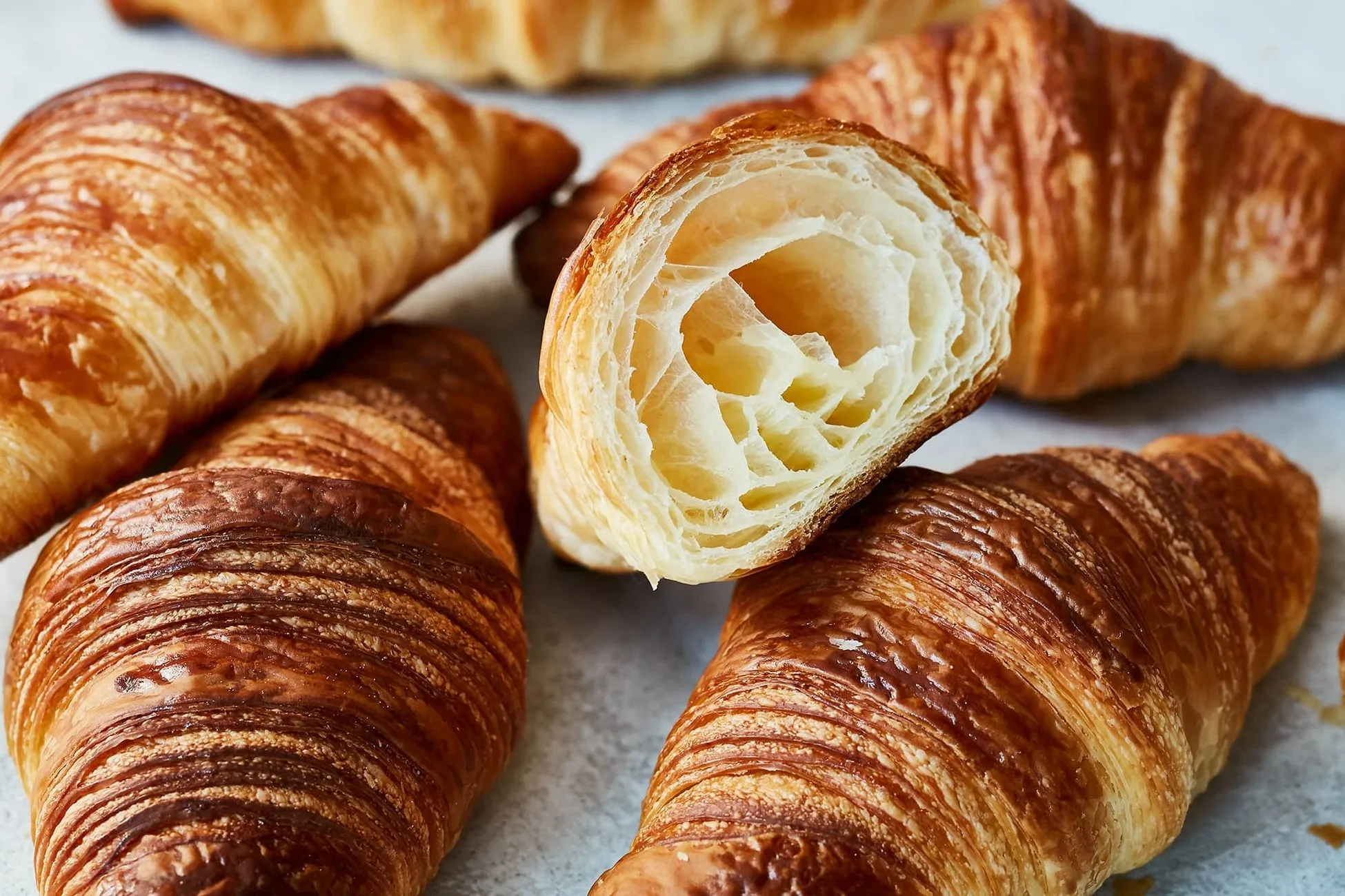クロワッサンがいくつか写っている写真。そのうちの1つは半分にカットされており、内側の層が見えている。