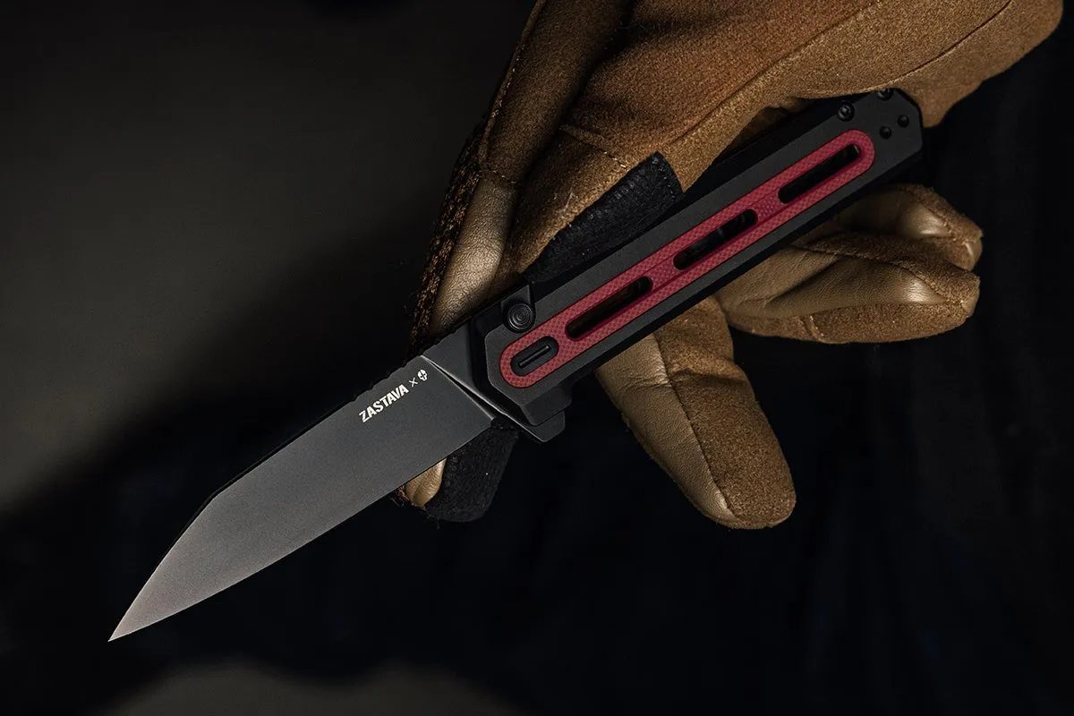 手袋をはめた手が、黒い刃と赤いアクセントのあるナイフを持っています。刃に「ZASTAVA x」