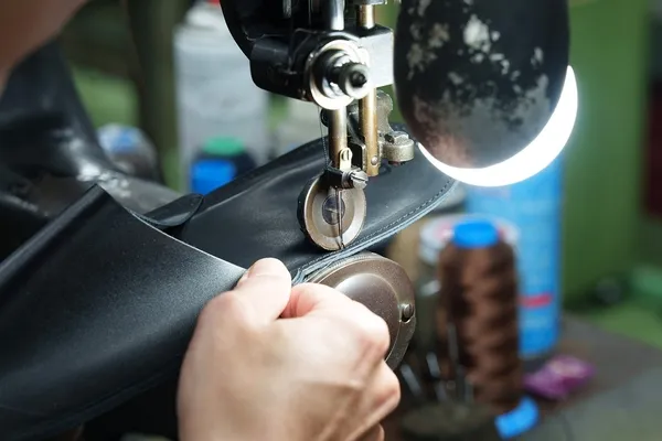 靴の製造工程を写した写真です。手作業で靴のパーツを縫い合わせている様子が写っています。