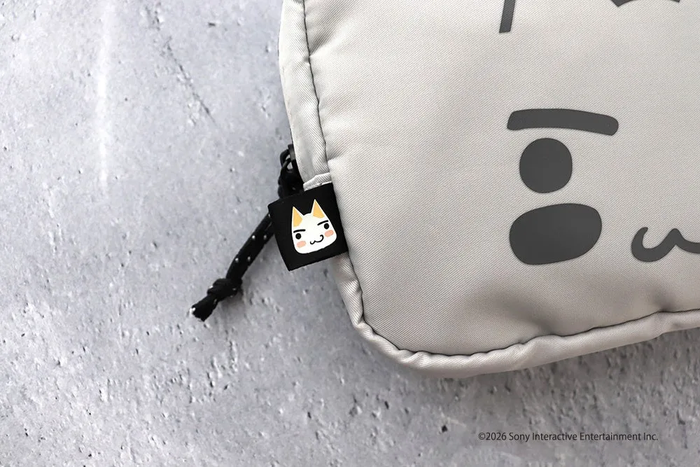 猫の顔が描かれたタグが付いたグレーのポーチのクローズアップ。ポーチには顔の模様が描かれており、背景はグレーの表面。