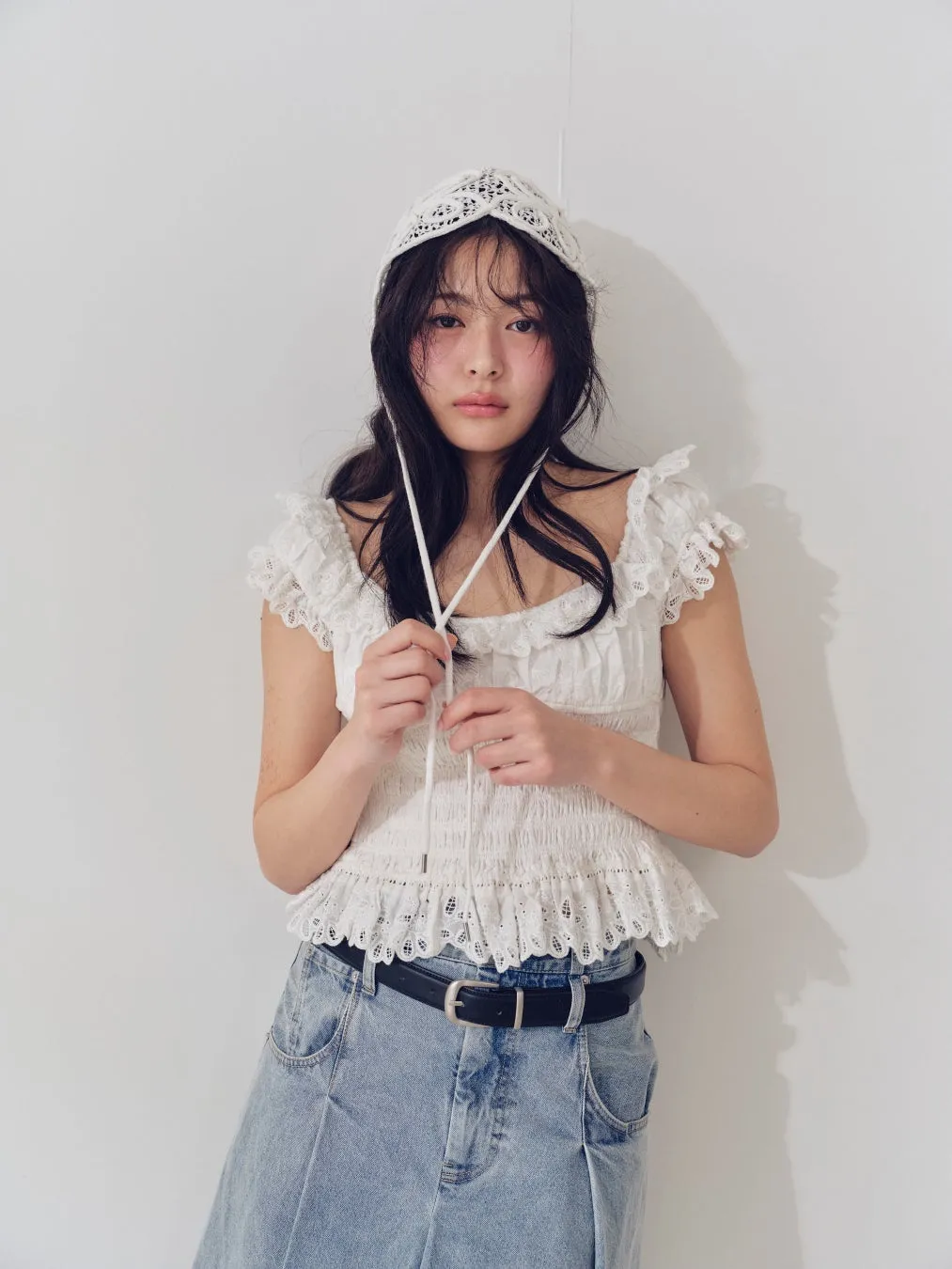 白レースの帽子とデニムパンツの女性