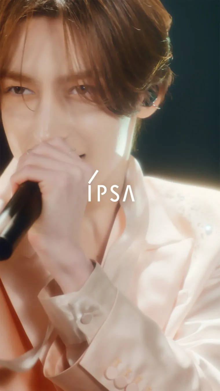 マイクを手に歌う男性のポートレート。男性はピンク色の服を着ており、ブランドのロゴが前景に表示されています。