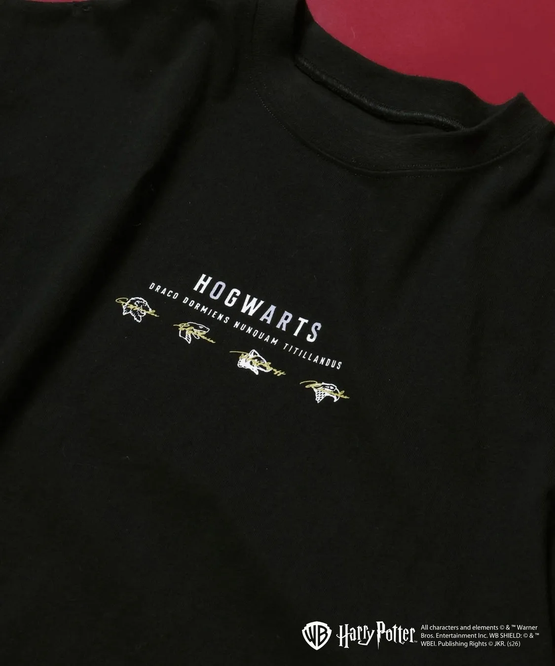 黒色のTシャツ。前面には「HOGWARTS」の文字と、その下にラテン語のフレーズが刺繍されている。さらに、ハリーポッターのロゴと著作権情報も含まれている。