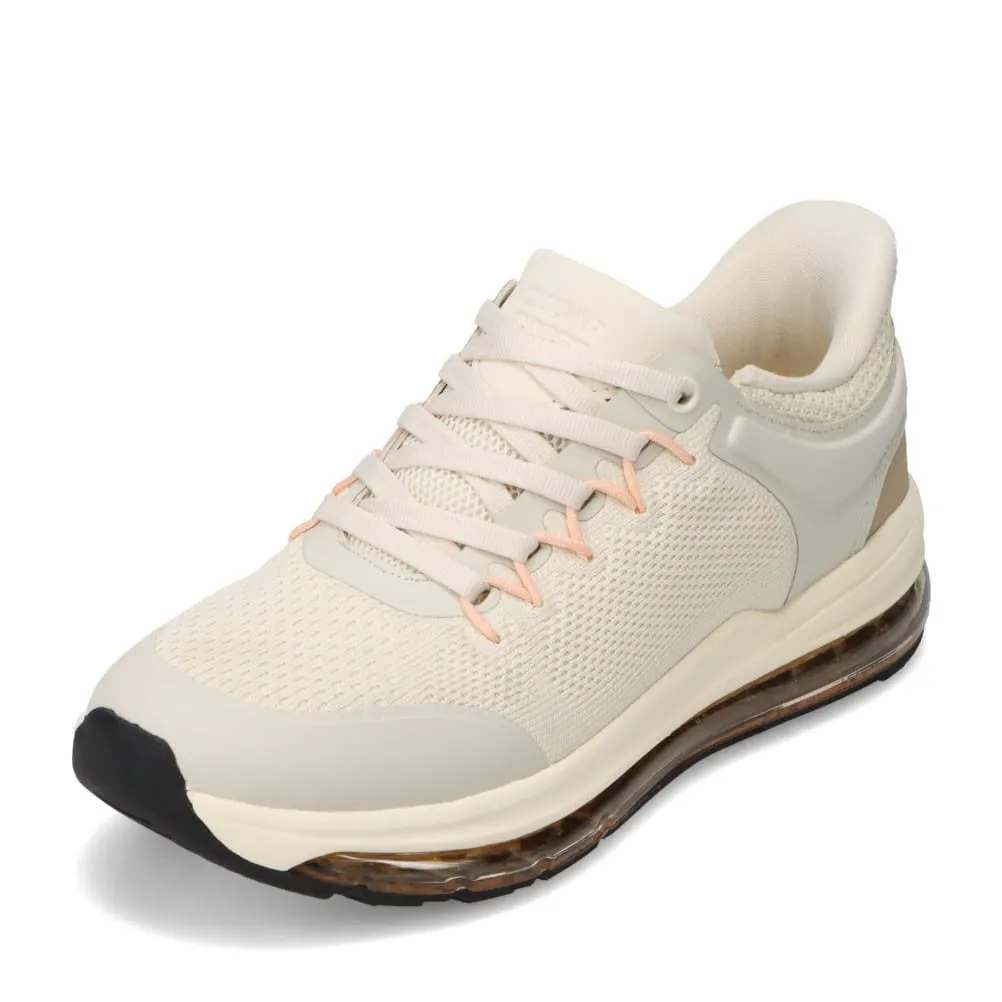 ベージュ色のスニーカーのクローズアップ写真。靴は白っぽい色合いで、メッシュ素材のアッパーとエアクッションソールが特徴です。シューレースとアッパーの一部には、アクセントとして淡いピンク色が使われています。