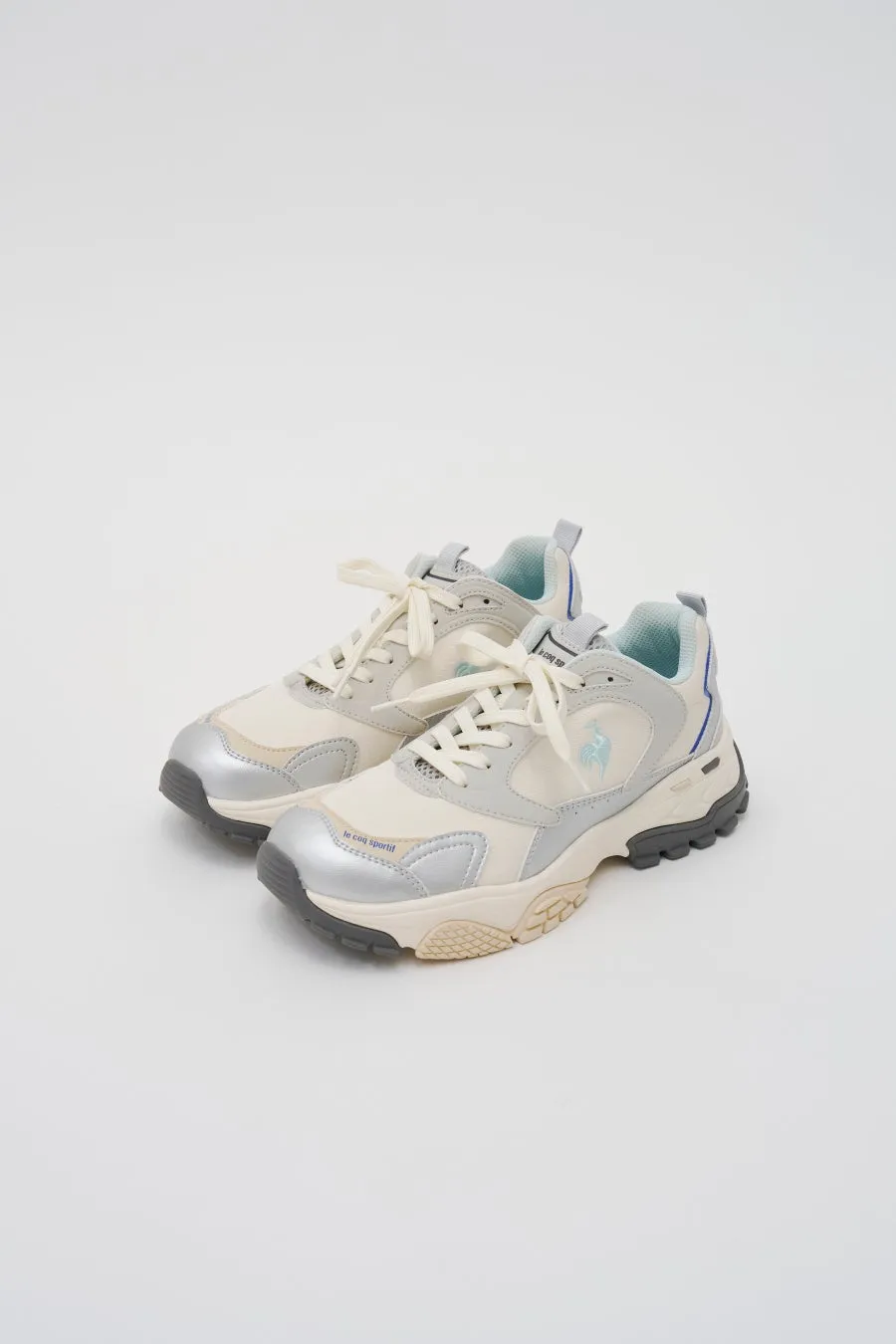 le coq sportifのロゴが見える白とグレーのスニーカー