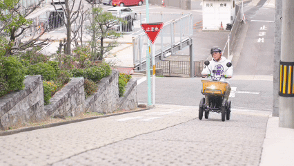 坂道を電動バイクで走行する男性