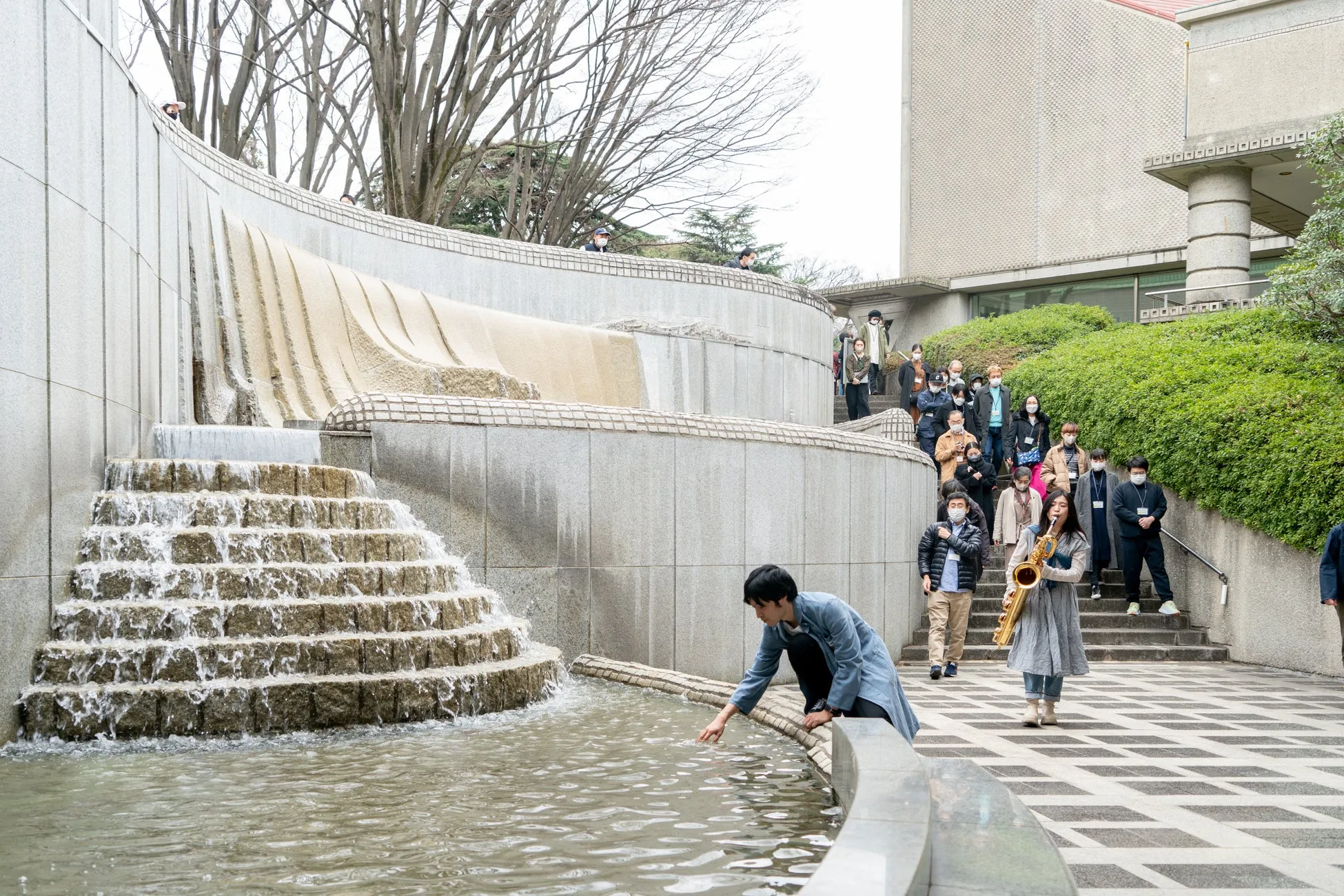 階段状の噴水と、楽器を演奏する女性や人々が写っている写真です。