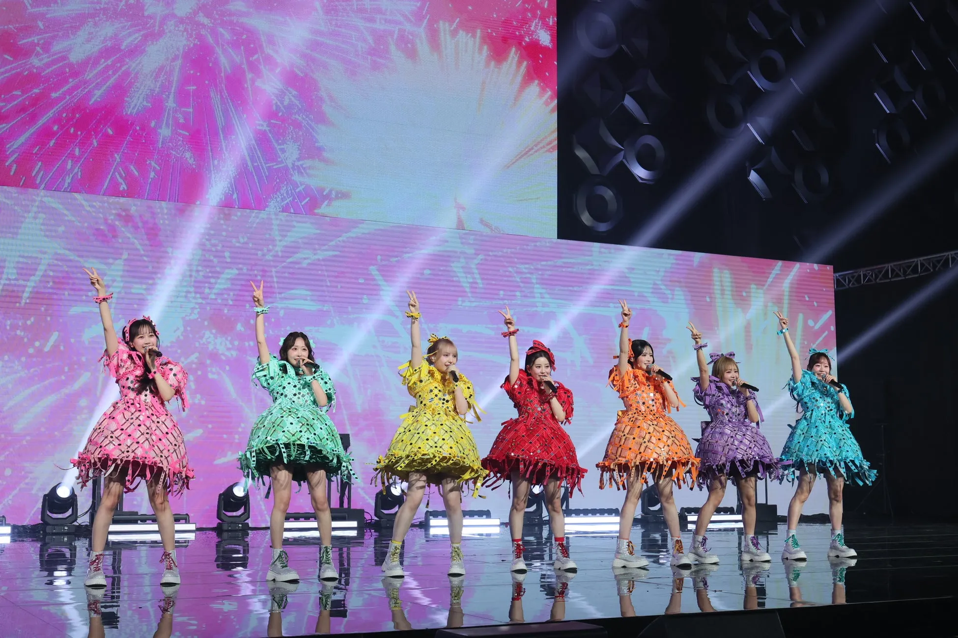 7人の女性アイドルがステージでパフォーマンスをしている様子