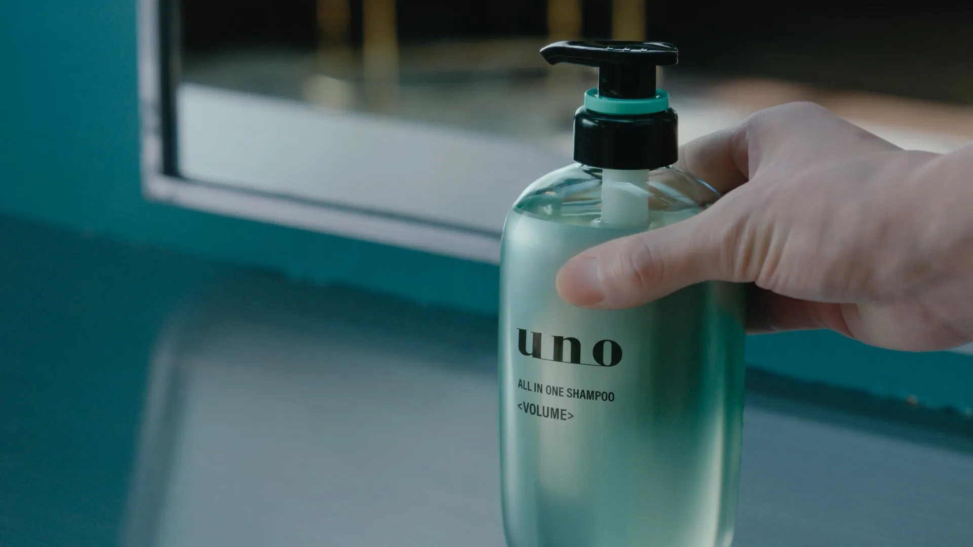 手に持たれたunoのオールインワンシャンプーのボトル