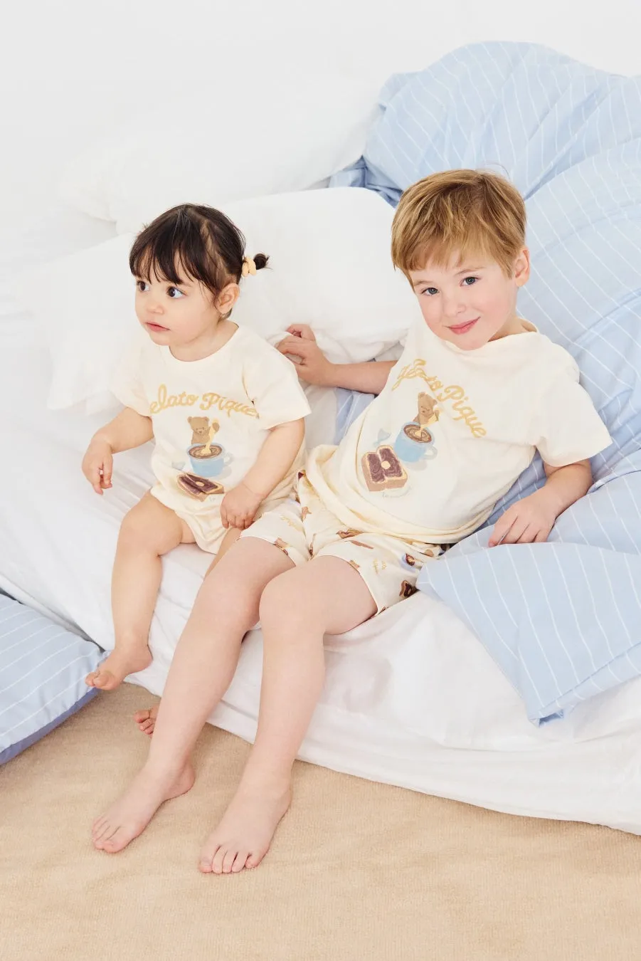 2人の子供がパジャマを着てベッドの上に座っている写真