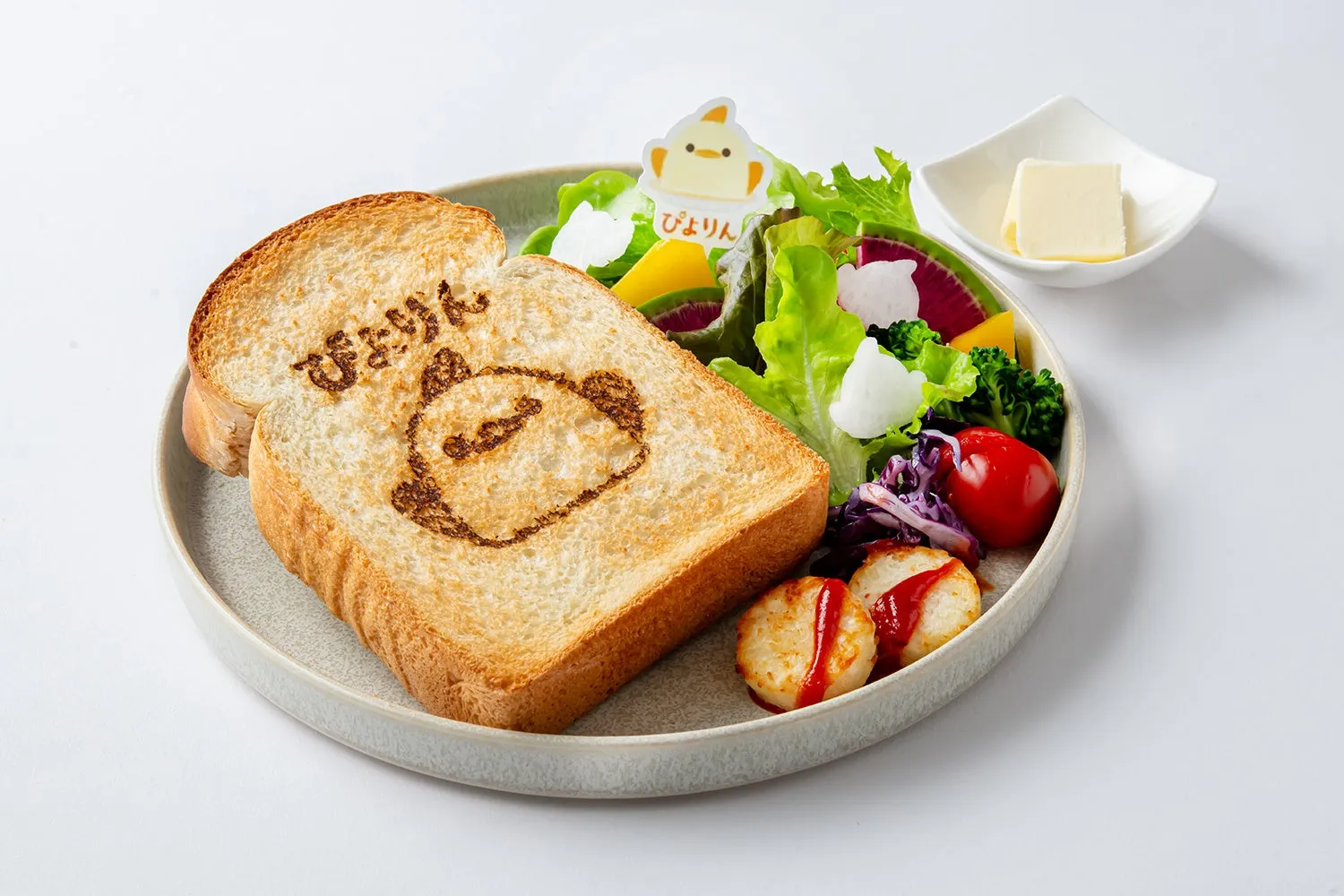 ぴよりんのイラストが描かれたトーストとサラダ、バターが添えられたおしゃれな朝食のイメージ。