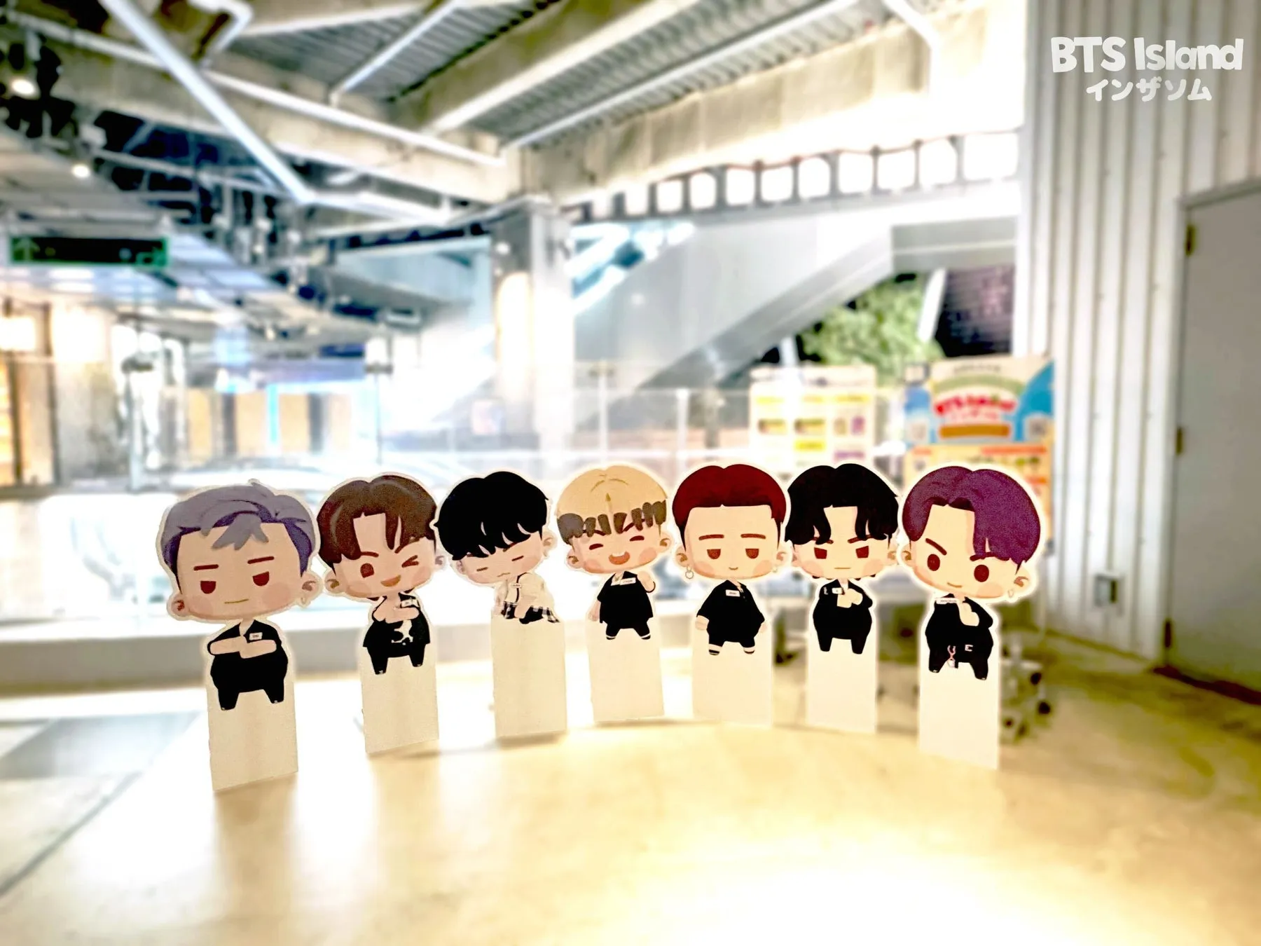 BTS Islandのキャラクターの切り絵が並んでいる写真。背景には商業施設のような場所が写っている。
