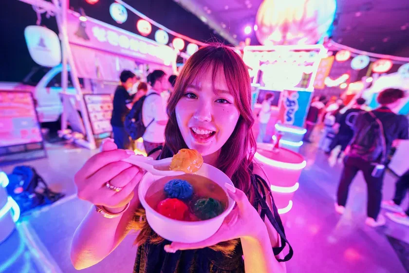 女性がカラフルなデザートを手に持ち、笑顔でカメラを見ている