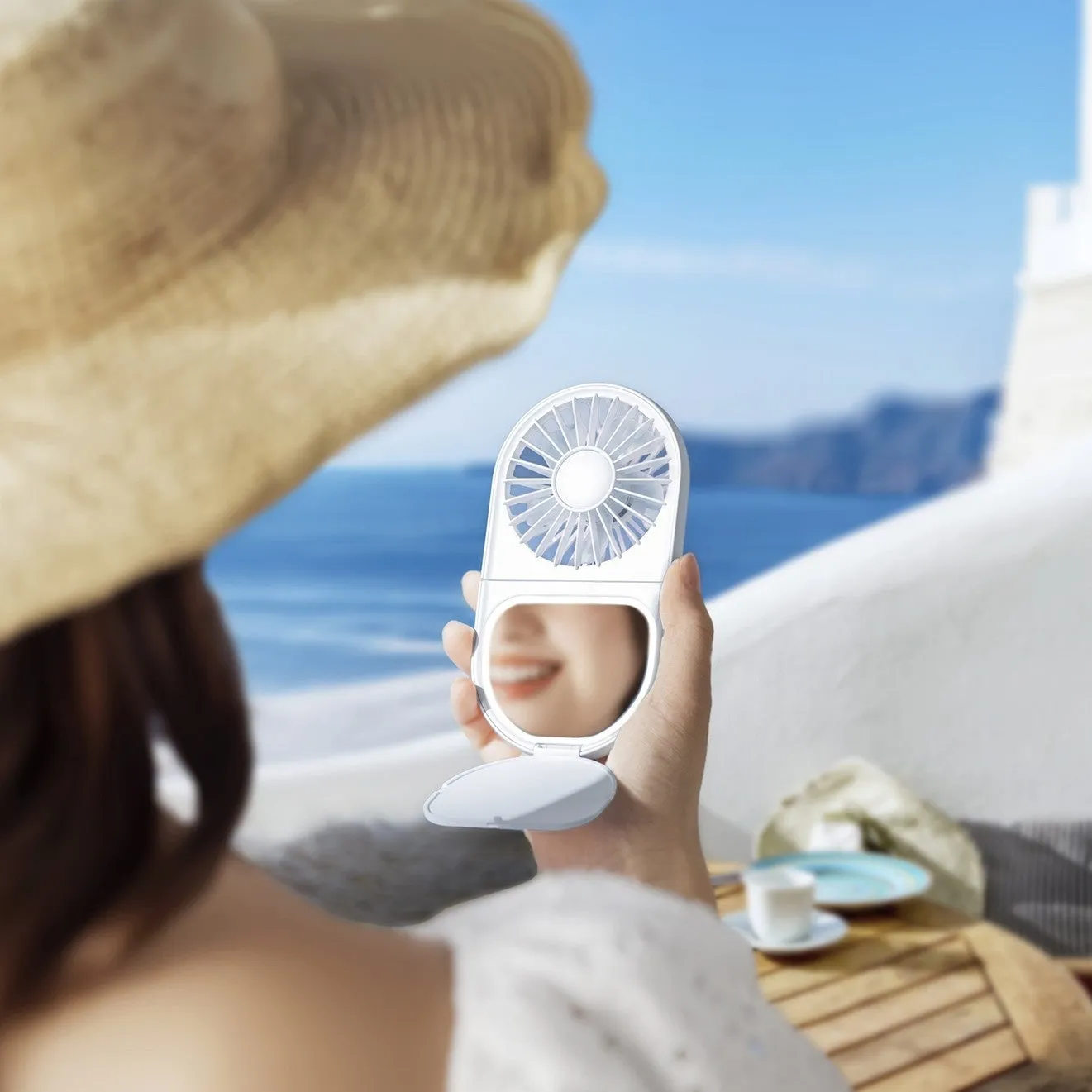 女性が手鏡と扇風機を持っている