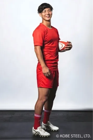 赤いユニフォームを着た男性がラグビーボールを持っています。