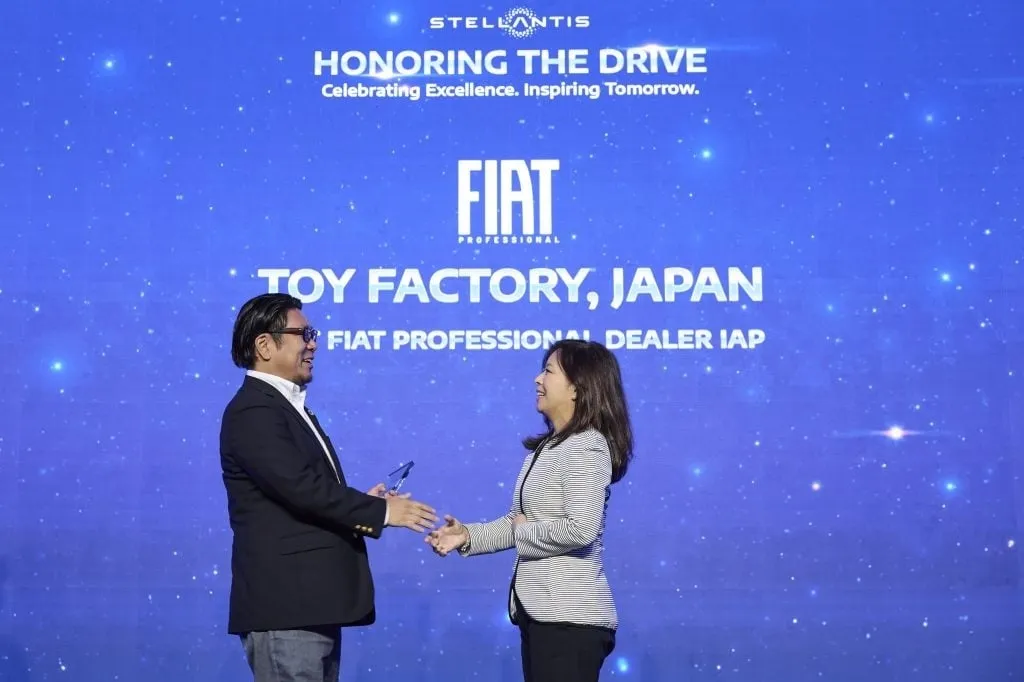 2人の人がステージ上で握手をしている写真