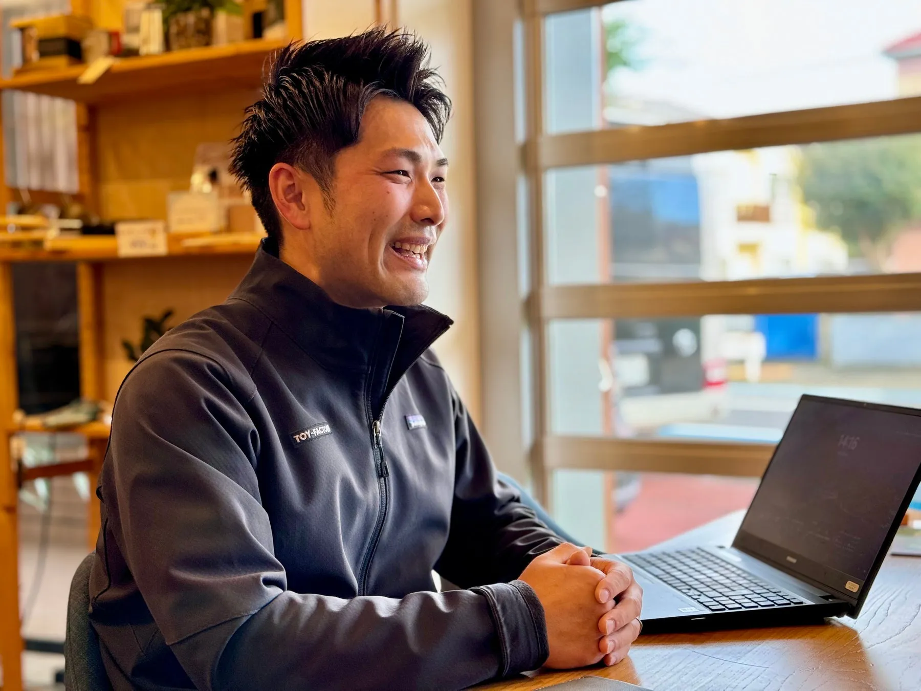 笑顔の男性がパソコンの前で座っている写真