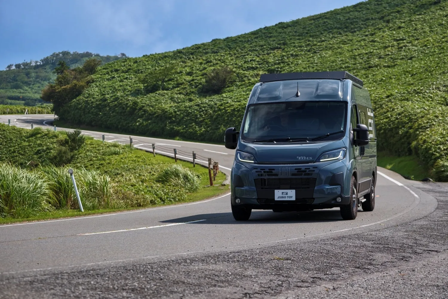緑豊かな山道を走る青色のキャンピングカー