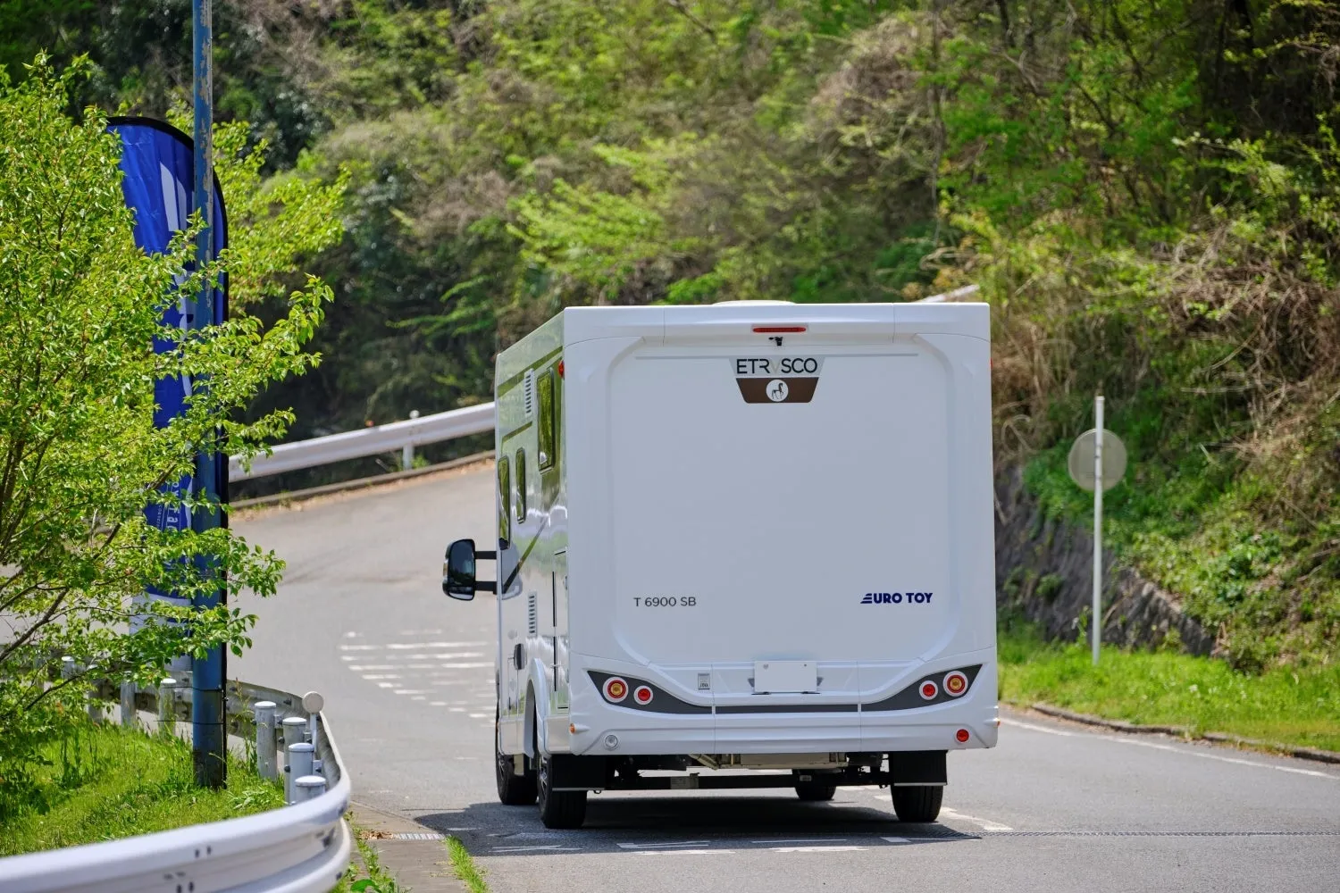 白いキャンピングカーが山道を走っている様子