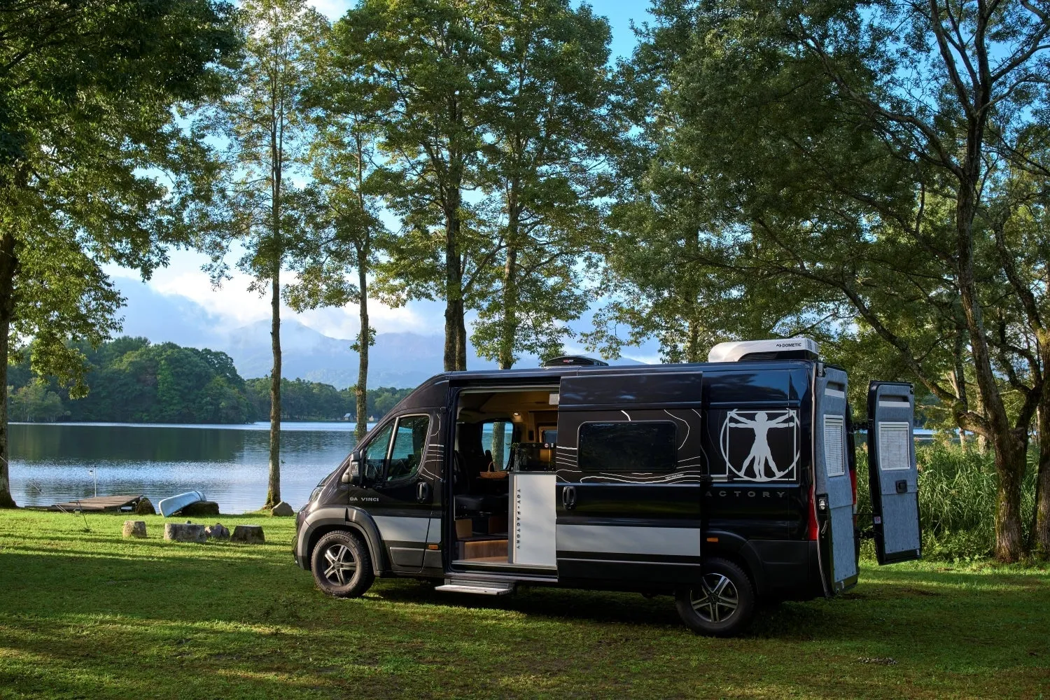 黒いキャンピングカーが湖畔の芝生に駐車されている様子