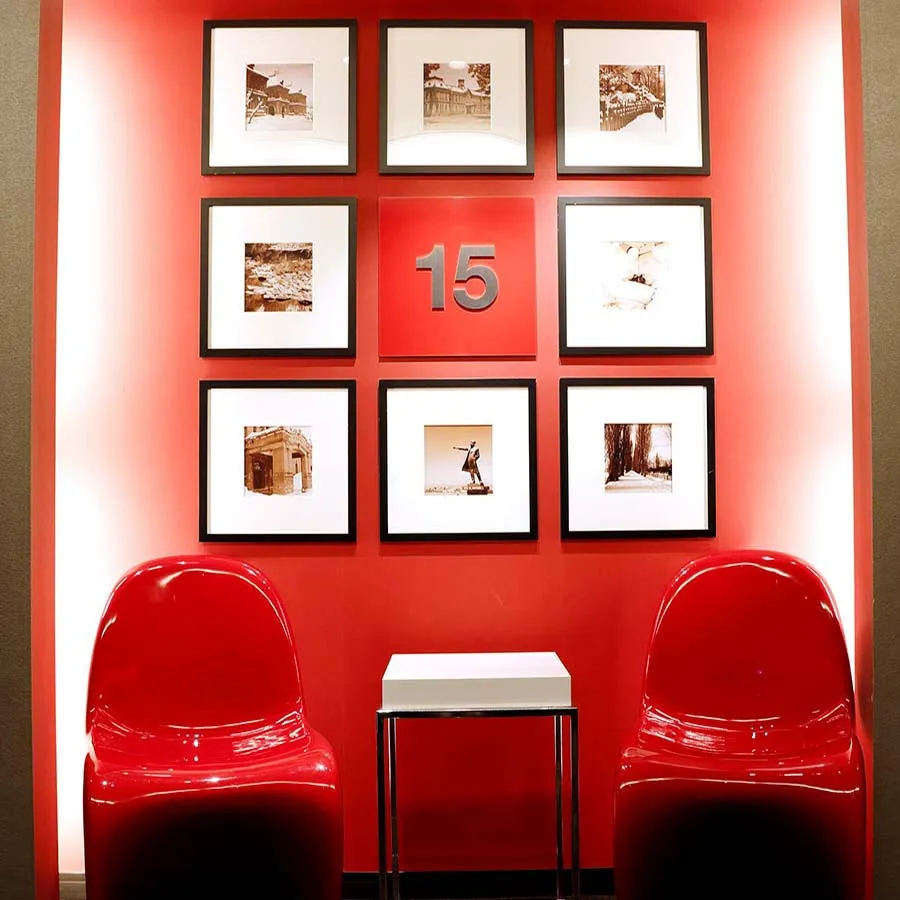赤い壁に飾られた複数の写真と、赤い椅子と白いテーブルが置かれた空間の写真。中央には「15」の数字が大きく表示されている。