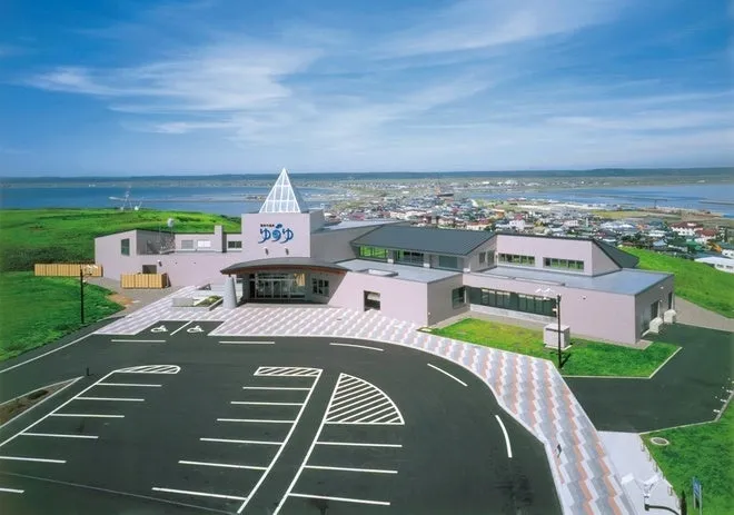 温泉施設の全景。モダンな建物で、青空が広がる