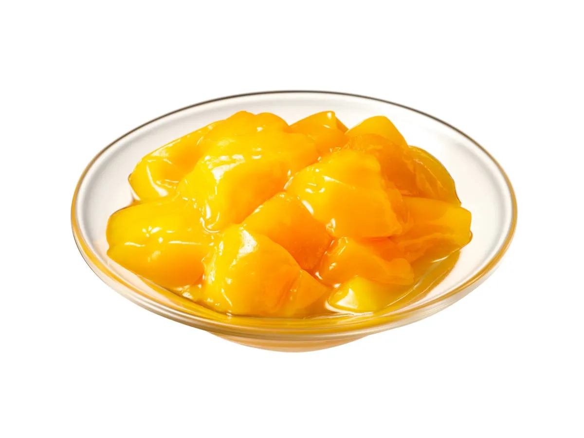 透明なガラスの器に入った、黄色いマンゴーのコンポートのクローズアップ写真です。マンゴーは一口大にカットされ、シロップに浸っています。