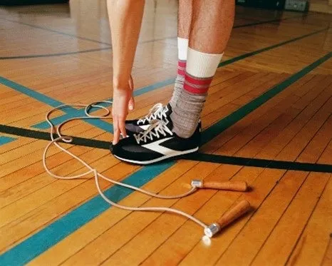 縄跳びをしている人の足元を捉えた写真。木製の床の上に縄跳びと、スニーカー、靴下が見える。