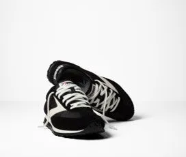 白を背景に、黒と白のランニングシューズのペアのクローズアップ。