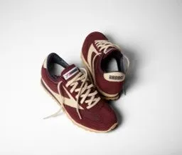 ブルックスの赤とベージュのランニングシューズのペアが白い背景に置かれています。